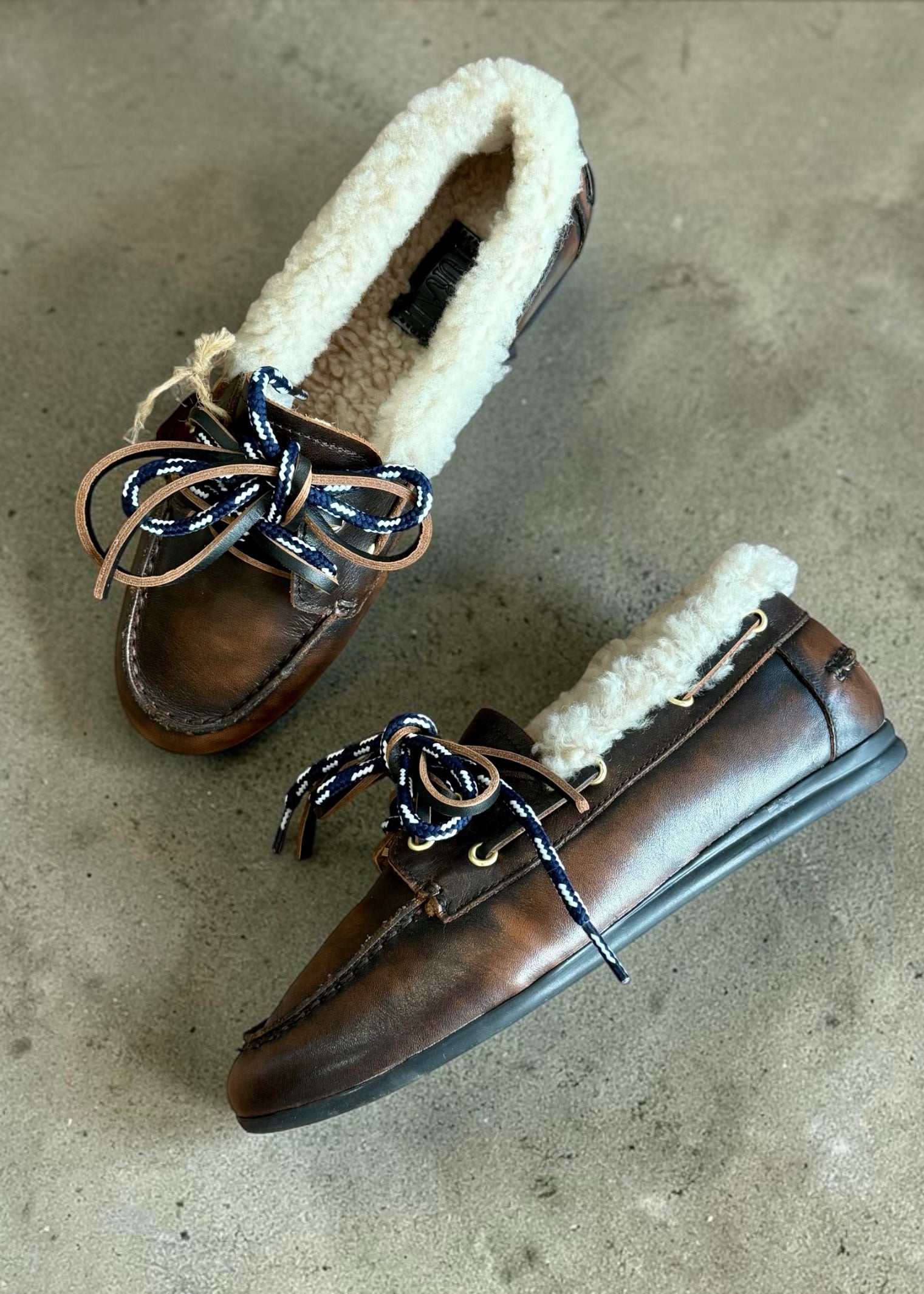 Mocassins Toral Nahua cuir marron fourrés avec fourrure et lacets en cuir sur fond en béton.